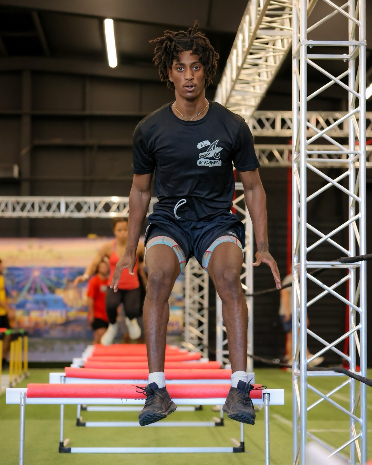 An athlete clearing a line of mini hurdles in a repeat-hop drill