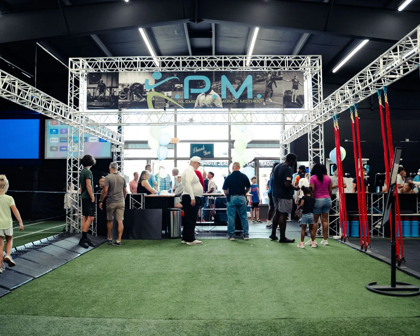 The KPM training floor: turf lanes under a lit truss with the KPM banner