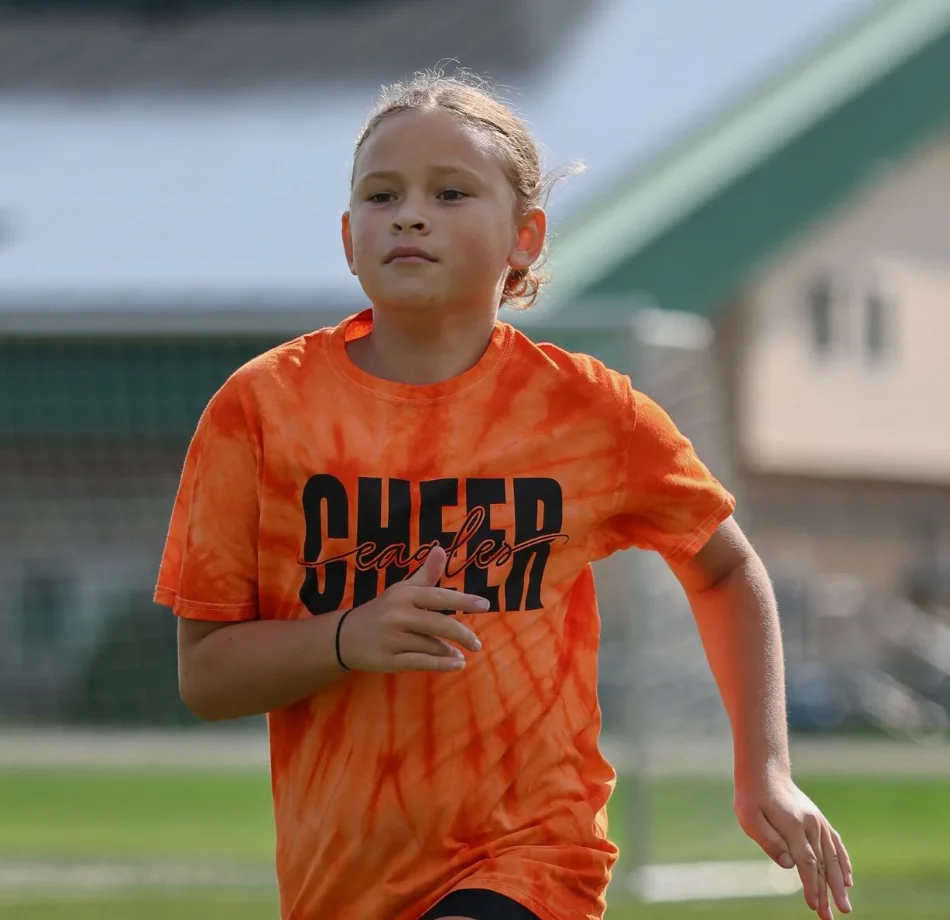 A young girl running on a turf field